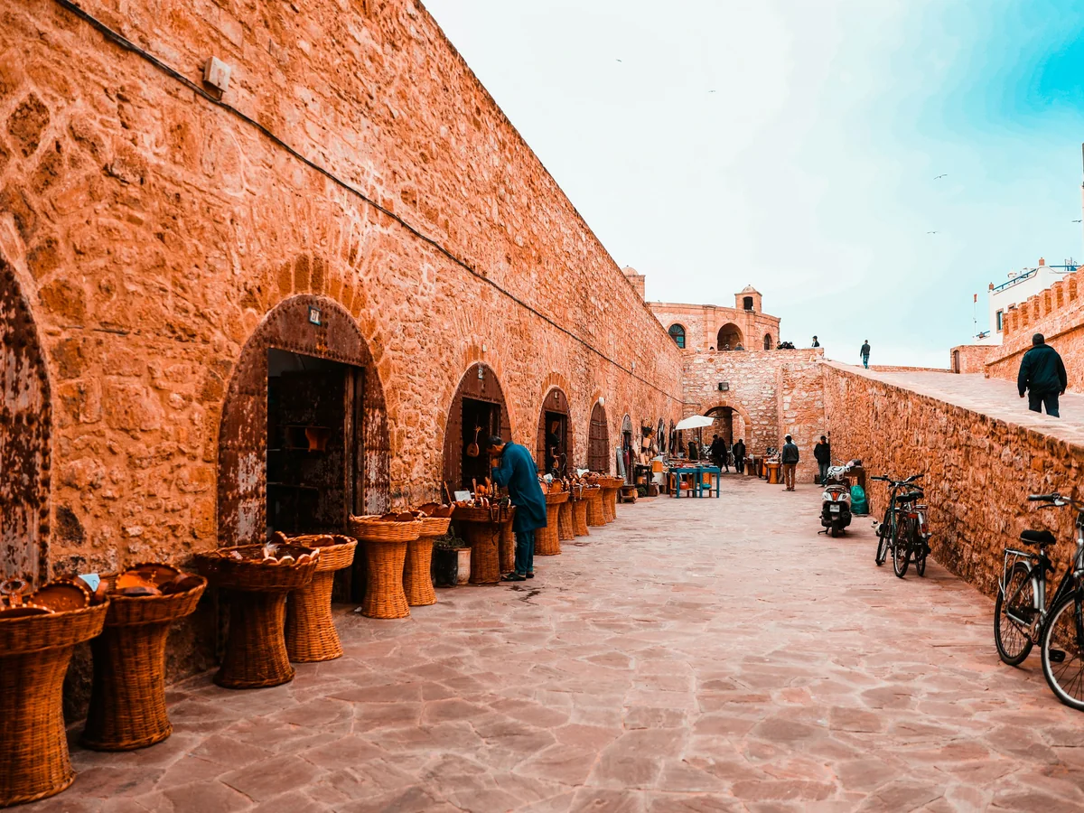 A stone lane inside Essaouira's medina near the ramparts, craft stalls and bicycles along the wall